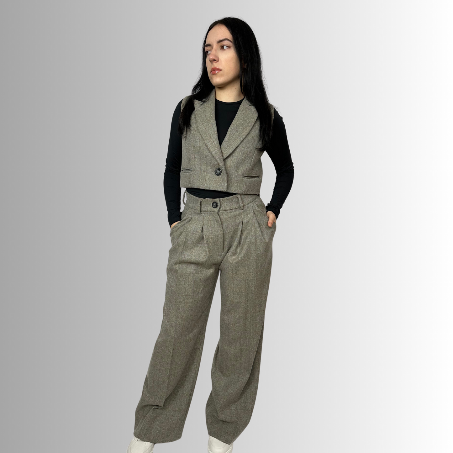 Front view of a woman wearing Sartorial Flair’s Zeo wide wool trousers in heather gray, styled with a black top and double-breasted blazer, hands on hips, showing high-waisted design.
