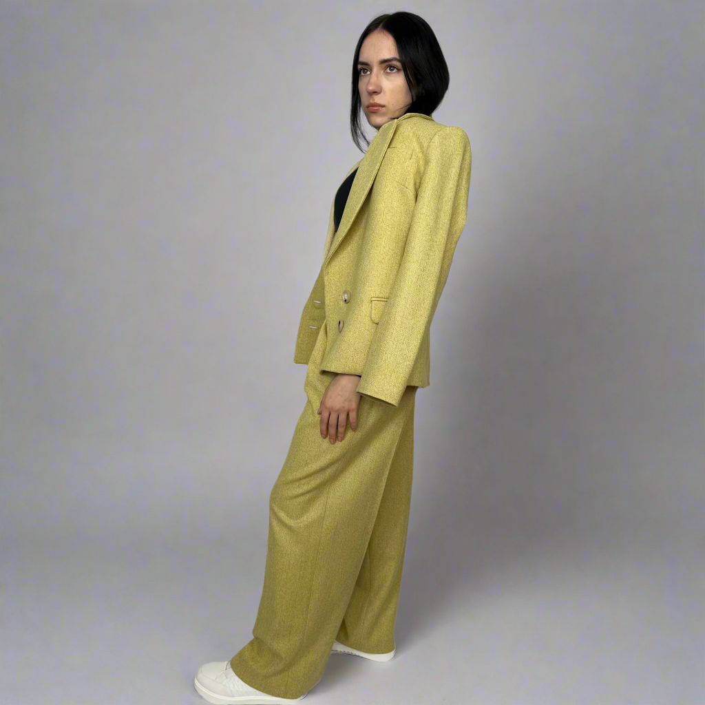 ide view of a woman modeling Sartorial Flair’s mustard wool suit, highlighting the elegant tailoring and timeless design, perfect for professional and formal occasions, made from sustainable materials.