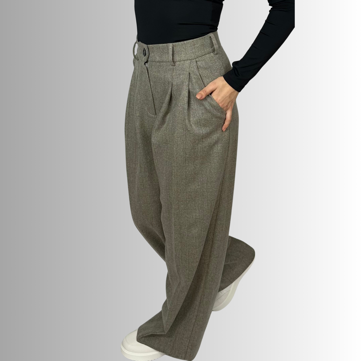 ide view of Sartorial Flair’s Zeo wide wool trousers worn by a woman, featuring a high waist and loose fit, paired with a fitted black top and sneakers.
