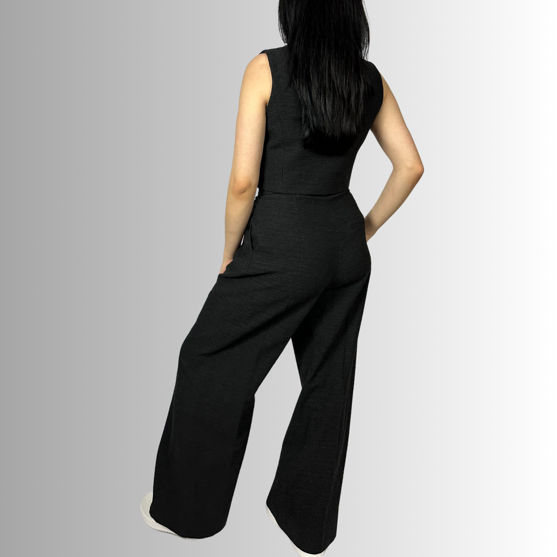 Rear view of a woman in Zara wide-leg wool trousers and waistcoat in charcoal black, showing the high waist design and intricate tailoring details at the back.