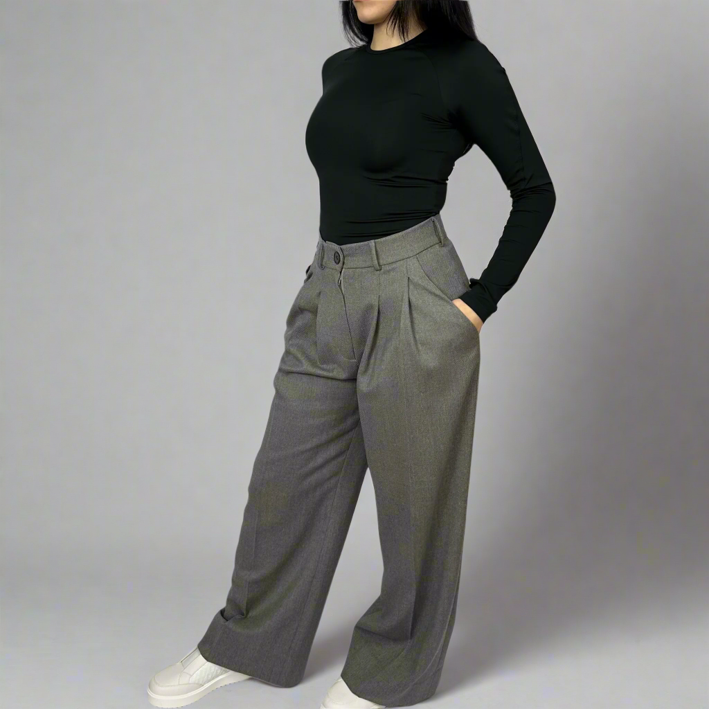 Model posing hands on hips wearing Isabella Charcoal Trousers, showcasing the structured waist and seamless design ideal for a professional yet fashionable look.