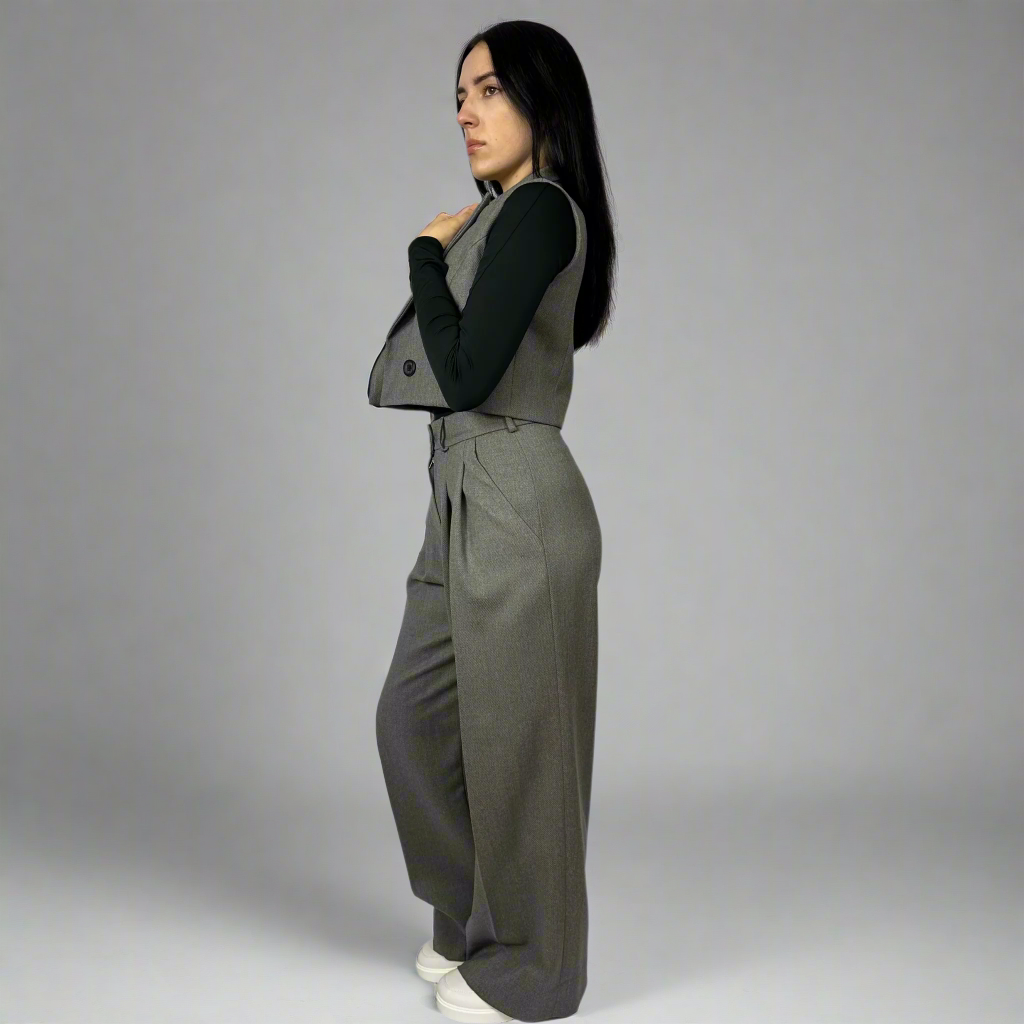 Side view of a model wearing Isabella Charcoal Wide-Leg Trousers, featuring a high waist and pleated details, emphasizing the tailored fit and luxurious feel of the fabric.
