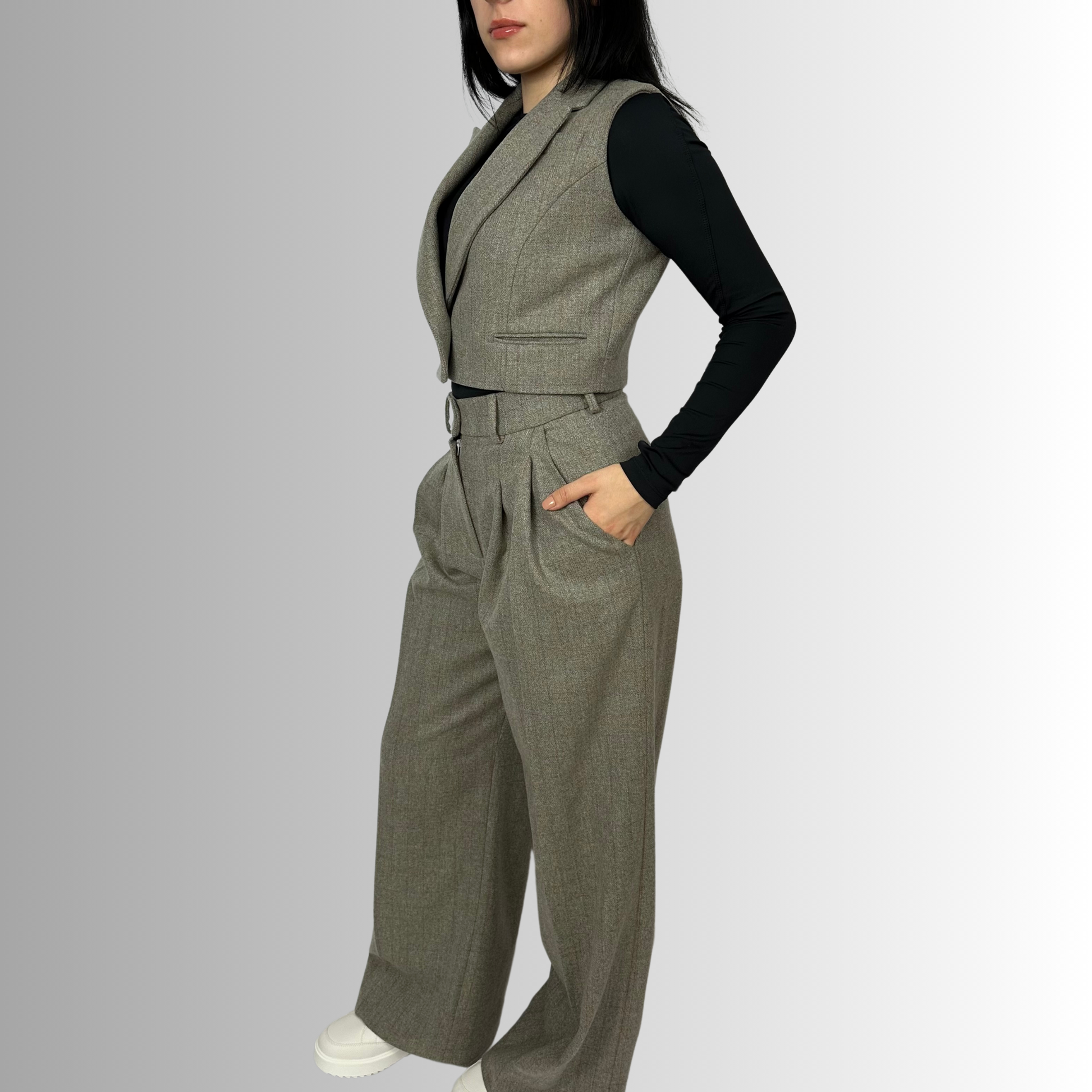 Side profile of a woman in a heather gray wool Zeo waistcoat by Sartorial Flair, showcasing the tailored fit and elegant waist cinching with a single button.