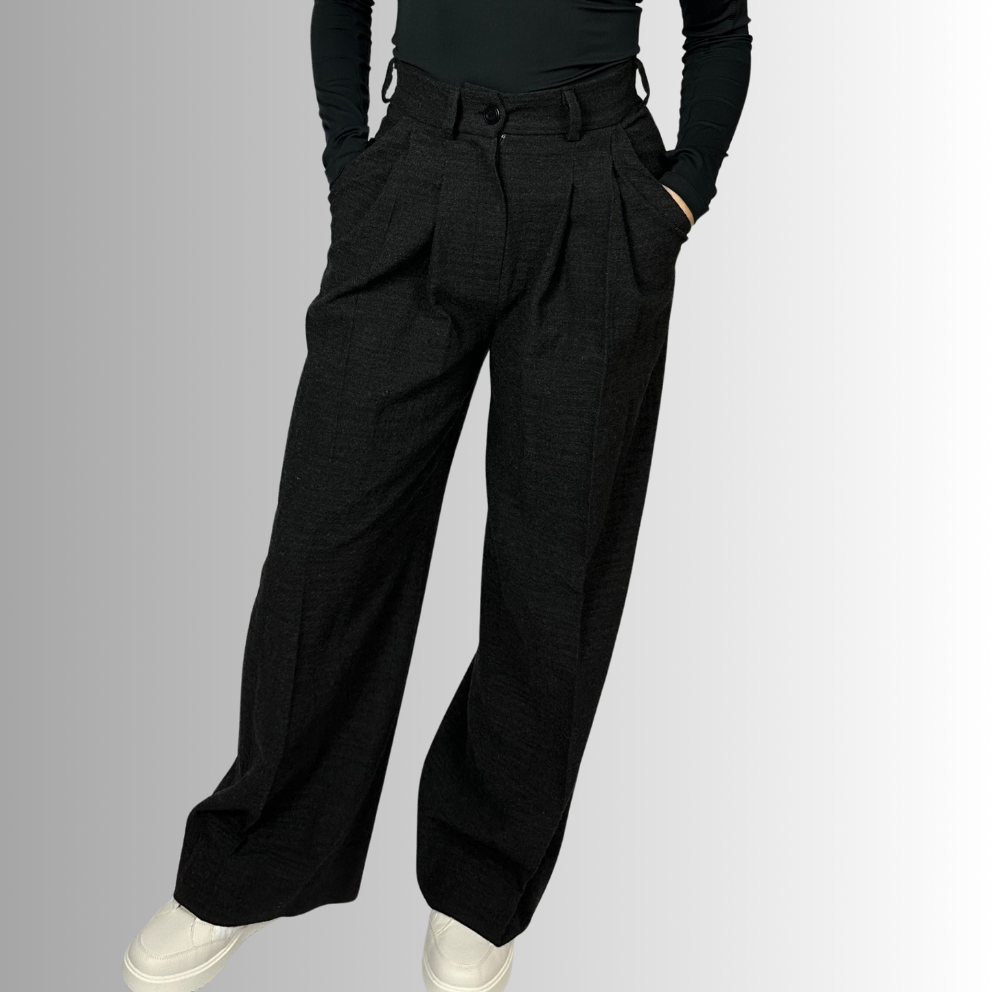 A view of a woman wearing Zara wide-leg wool trousers in charcoal black, paired with a fitted black top, showcasing the high-waisted design and loose fit of the trousers.
